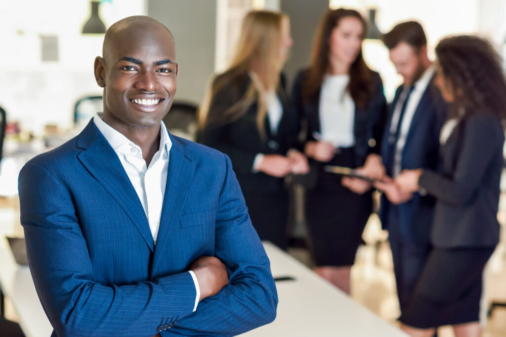 A young, confident business professional with his team in the background.