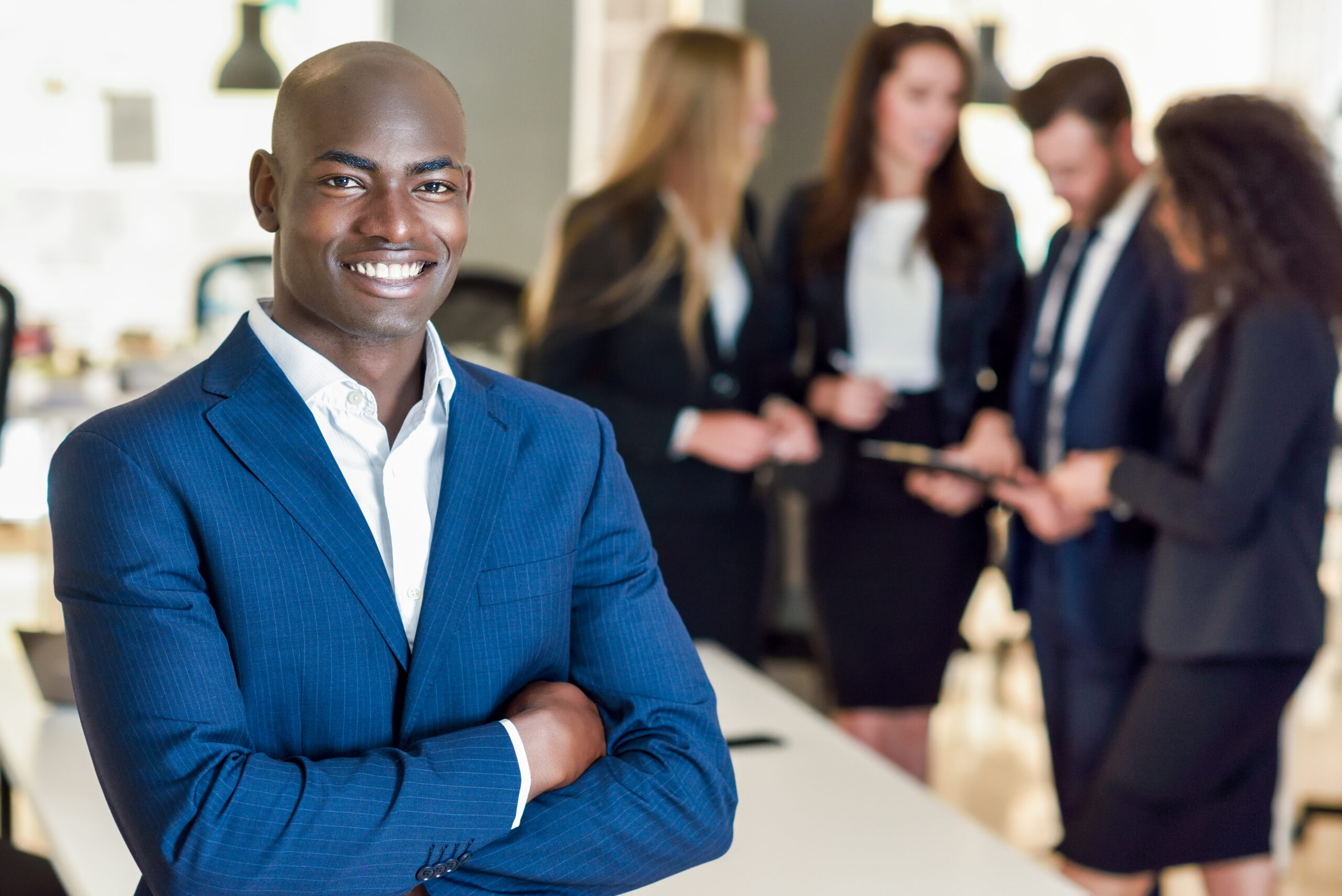 A young, confident business professional with his team in the background.