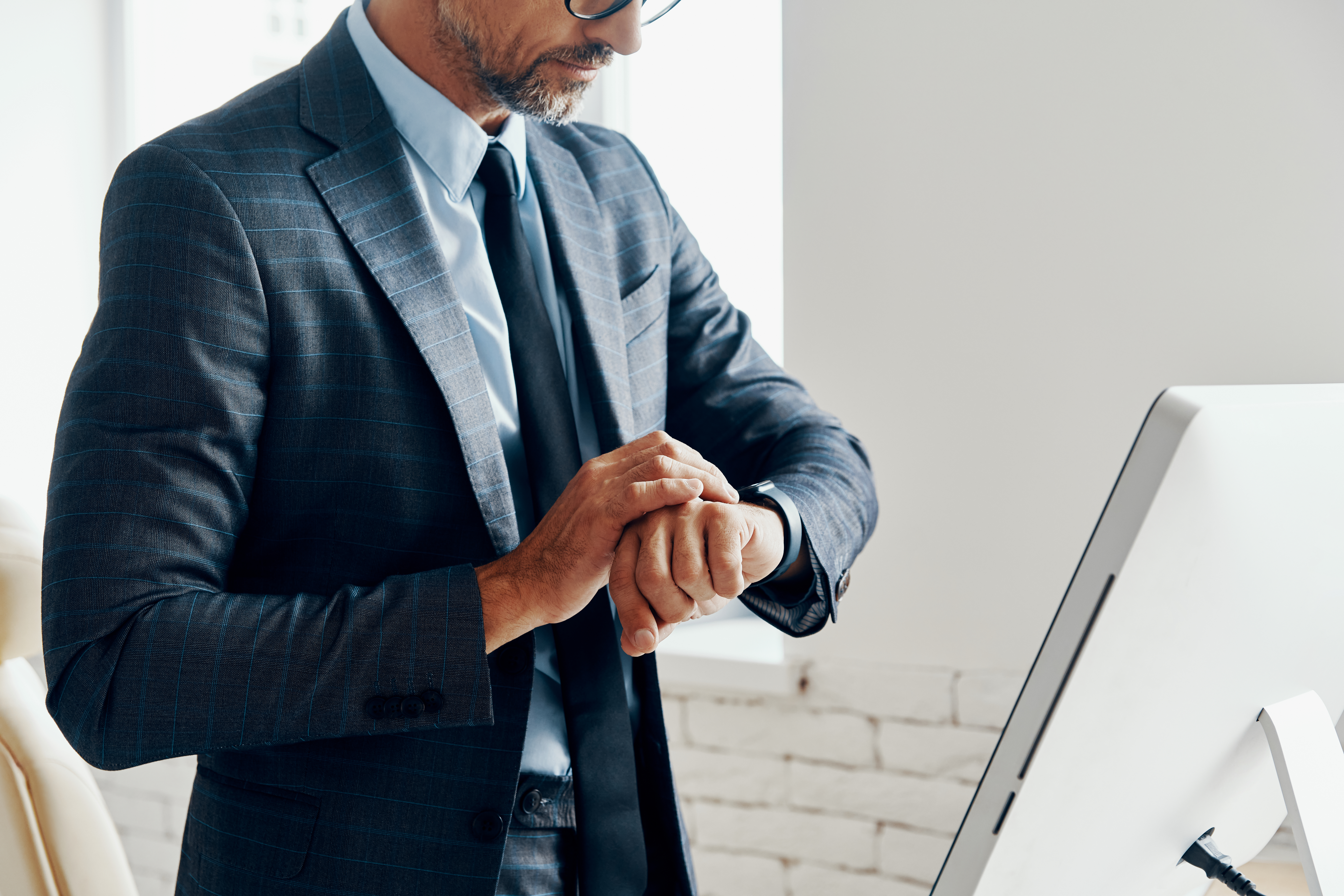 A business professional looking at his wristwatch in his office.