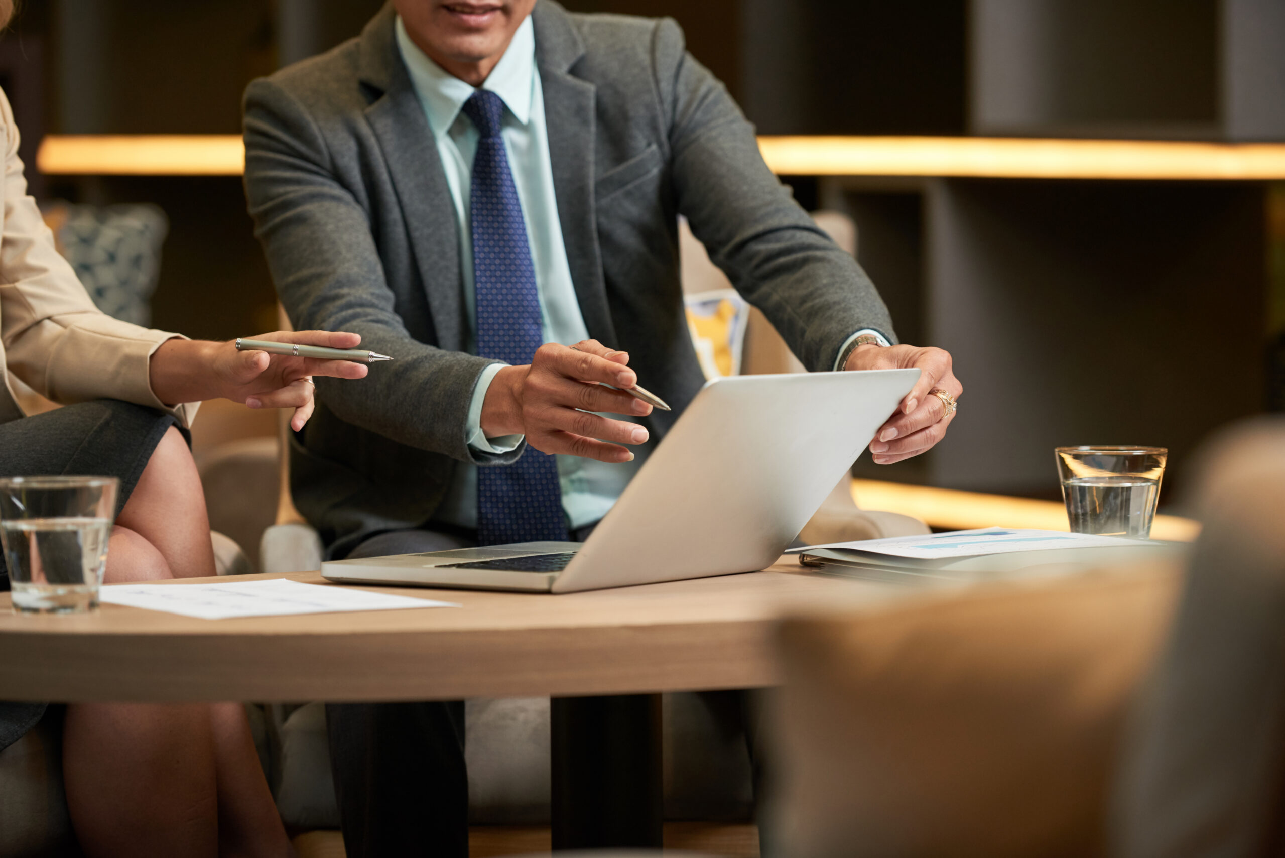 Two business professionals having a meeting while looking at a laptop on a table in a more relaxed environment
