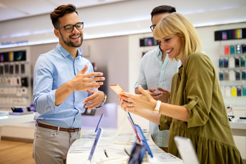 A sales professional happily educating two clients in a modern store setting.
