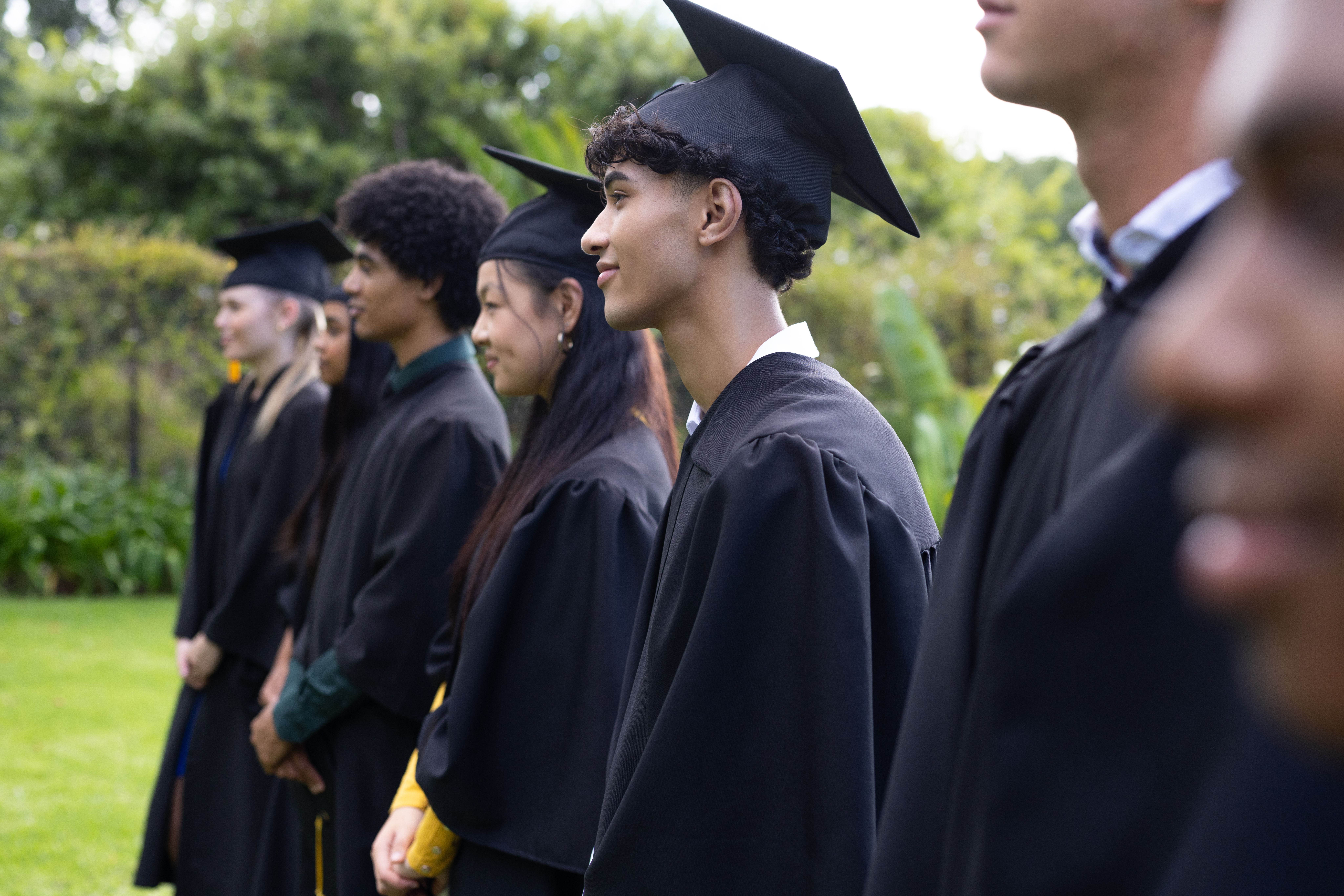 A group of young graduates wearing black graduation gowns and hats