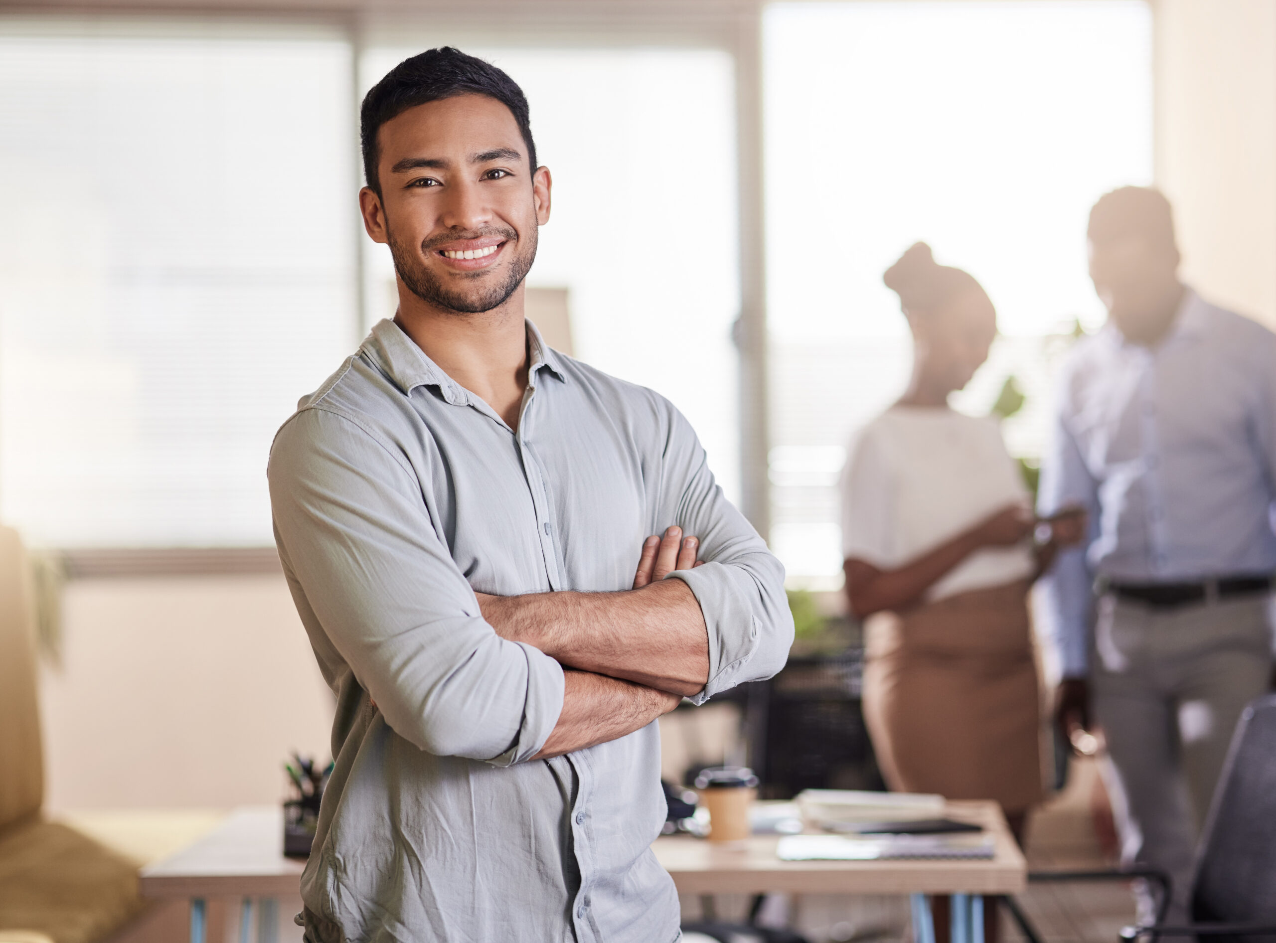 A young professional in a bright office with his colleagues discussing in the background
